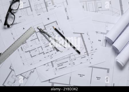 Diversi disegni architettonici, righello, divisore, matita e vetri sul tavolo, disposizione piatta Foto Stock