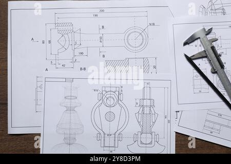 Disegni tecnici diversi, calibro a corsoio e matita su tavolo in legno, vista dall'alto Foto Stock