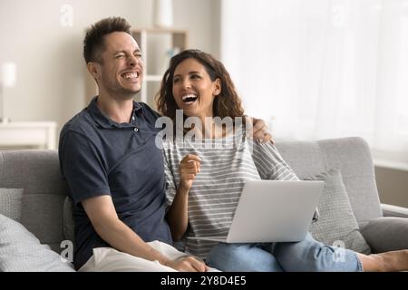 Felice felice felice felice marito e moglie seduti sul divano con gadget Foto Stock