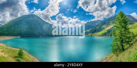 Acque turchesi che riflettono il cielo azzurro di una soleggiata giornata estiva sul Lago di Vernago in Trentino alto Adige Foto Stock