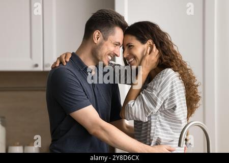 Allegra e romantica giovane coppia in piedi vicino, ridendo in cucina Foto Stock