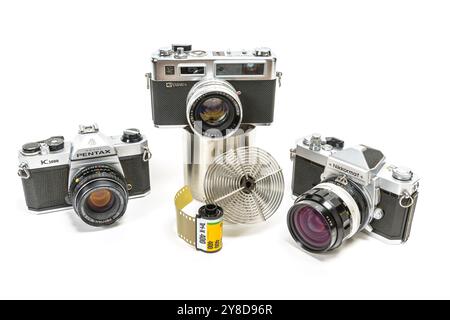 Maryville, Tennessee, Stati Uniti – 1° ottobre 2024: Ripresa orizzontale di tre vecchie telecamere da 35 mm, rotolo di pellicola e un carro armato per sviluppatori di film con bobina. Foto Stock