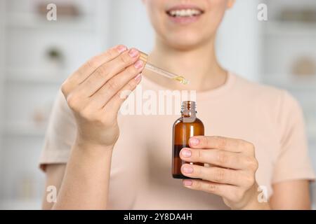 Giovane donna che prende tintura CBD all'interno, primo piano Foto Stock