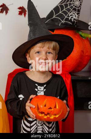 Ragazzo felice in spaventoso travestimento del mago che tiene in mano la zucca intagliata Foto Stock