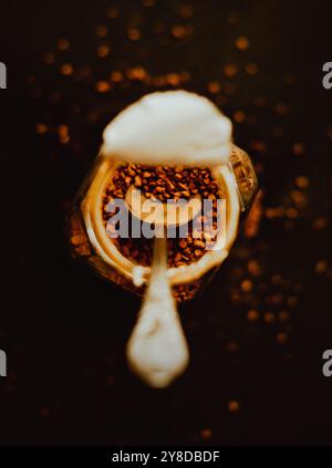 Vista dall'alto di un barattolo di caffè istantaneo forte con un cucchiaino d'argento su uno sfondo scuro per la colazione. L'amore per il caffè la mattina. Foto Stock