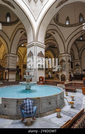 Bursa, Turchia - 7 settembre 2024: Un uomo si lava nella fontana della grande Moschea di Bursa in Turchia. Foto Stock