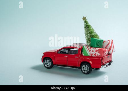 Un camion rosso è decorato con un albero di Natale e regali. La scena è festosa e gioiosa, con il veicolo al centro dell'attenzione Foto Stock