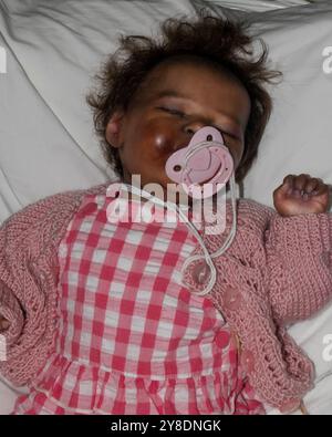 Bambola rinata che indossa abiti rosa, bambola realistica che dorme a letto Foto Stock