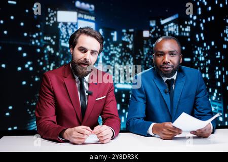 Team di giornalisti diversi che riportano notizie in diretta in media studio, presentando gli argomenti più recenti per le comunicazioni globali. Giornalisti che lavorano come ospiti di spettacoli notturni creando divertenti contenuti televisivi. Foto Stock