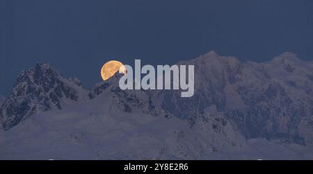 La luna emerge da dietro le montagne di Denali Foto Stock