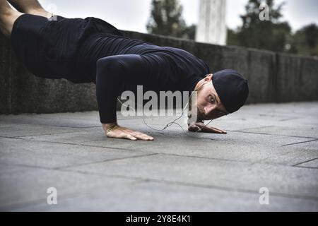 Il giovane sportivo con barba si allena in un parco, facendo una serie di push up all'aperto Foto Stock