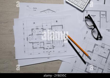 Diversi disegni architettonici, calcolatrice, vetri e matite su tavolo in legno, vista dall'alto Foto Stock