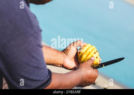 Uomo che taglia l'ananas con precisione. Delizia fresca dell'ananas Foto Stock