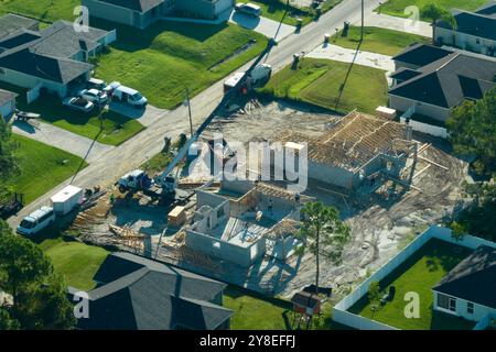 Costruttori professionali e gru camion che lavorano sulla costruzione di tetti di casa suburbana non finita con struttura a telaio in legno nella zona rurale della Florida. Conc Foto Stock