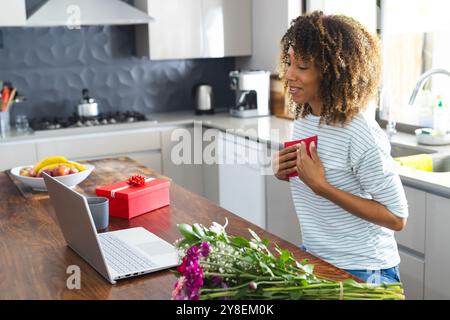 Una donna birazziale si gode una pausa caffè a casa Foto Stock
