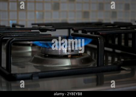 Il bruciatore singolo su un piano cottura a gas naturale è acceso e blu acceso. Foto Stock