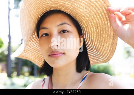 Ritratto di donna asiatica con capelli corti che indossa un cappello da sole in giardino a casa Foto Stock