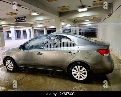 Cairo, Egitto, 19 settembre 2024: Pulizia di un veicolo KIA Cerato con acqua direttamente sul corpo dell'auto, spruzzi d'acqua su un'auto coreana in un garage, acqua Foto Stock