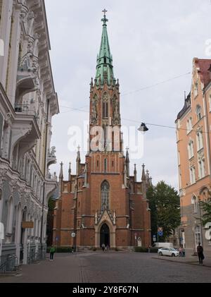 Riga, Lettonia - 15 settembre 2024: Vecchia chiesa evangelica luterana di Santa Gertrude. Gente che cammina a riga. Strade, edifici. Stile di vita nell'area urbana. Foto Stock