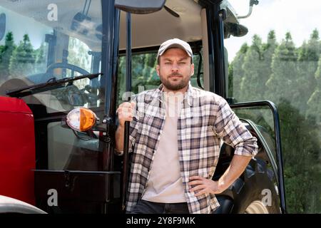 Uomo conducente trattore agricolo. Operatore attrezzatura di registrazione. Foto Stock