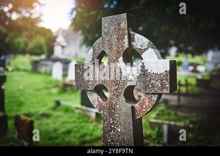 Croce celtica, lapide d'epoca e cimitero per la pace, i funerali e la memoria all'aperto. Crocifisso cristiano, vecchia lapide e cimitero per cattolici Foto Stock