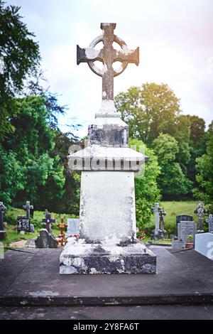 Croce celtica, lapide d'epoca e cimitero per la pace, i funerali e la memoria all'aperto. Crocifisso cristiano, vecchia lapide o cimitero per cattolici Foto Stock