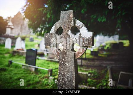 Croce celtica, antica lapide e cimitero per la pace, la memoria e la memoria all'aperto. Crocifisso cristiano, lapide d'epoca e cimitero per cattolici Foto Stock