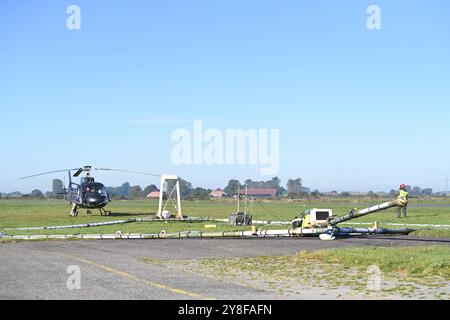 Geophysikalische Messungen mit Hubschrauber. Ein Mitarbeiter der firma SkyTeam weißt den Hubschrauber ein. DAS Niedersächsische Landesamt für Bergbau, energie und Geologie tätigt derzeit unter anderem in Ostfriesland geophysikalische Messungen mit Blick auf das Grundwasser, die von einem Hubschrauber unterstützt werden. Dabei wird vom 4. bis voraussichtlich zum 16. Oktober eine große antenne in etwa 30 Metern Höhe über die Geländeoberfläche geschleppt. Durch das sogenannte SkyTEM-Verfahren solle bei Flügen rund um Emden, Leer, Aurich, Cloppenburg und auch im Ammerland bei Oldenburg mit der Ant Foto Stock