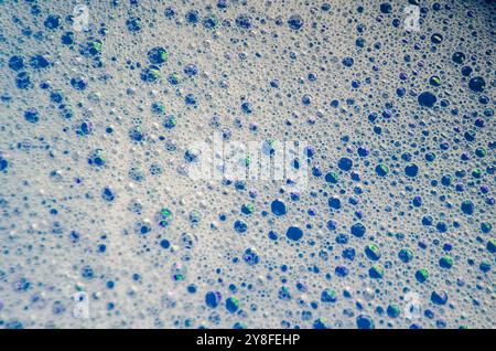 Vista macro delle bolle che si formano sulla superficie dell'acqua con sfondo blu. Foto Stock