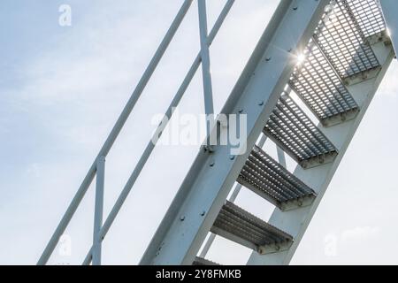 scala in acciaio con gradini in lamiera forata contro la luce Foto Stock