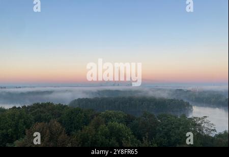 Duisburg, Germania. 5 ottobre 2024. La nebbia mattutina si propaga sull'area ricreativa di Sechs-seen-Platte, con le acciaierie ThyssenKrupp sullo sfondo. Crediti: Ulf Zimmermann/dpa/Alamy Live News Foto Stock