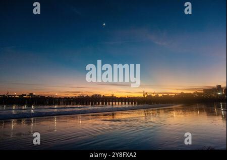 Una luna crescente mette in evidenza uno splendido tramonto al Molo di Santa Cruz. Foto Stock
