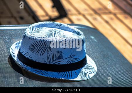 Una scena rilassata con un cappello da uomo appoggiato su un lettino, che cattura l'essenza di una piacevole giornata in spiaggia o a bordo piscina. Foto Stock