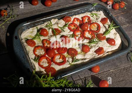 Focaccia appena sfornata con pomodori, olive, aglio ed erbe aromatiche, vista dall'alto, spazio copia. Foto Stock
