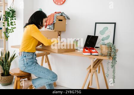 Donna freelance di piccole imprese che prepara pacchetti per la consegna al cliente Foto Stock