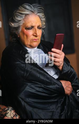 Autorevole giudice senior sta vivendo mentre legge le notizie sul suo smartphone. È vestita con il suo abbigliamento professionale e sembra che stia prendendo piede Foto Stock