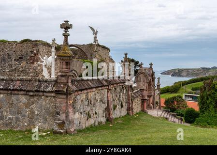 Tranquillo e storico cimitero in pietra con sculture intricate e statue di angelo che si affacciano sull'oceano, situato a Comillas, sull'oceano Atlantico Foto Stock