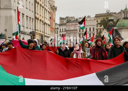 Cracovia, Polonia. 5 ottobre 2024. I manifestanti detengono bandiere palestinesi durante la manifestazione i palestinesi, i libanesi e i loro sostenitori hanno protestato a sostegno della Palestina e contro le azioni di guerra israeliane nella Striscia di Gaza, in Cisgiordania e in Libano nella piazza principale della città vecchia di Cracovia. Credito: SOPA Images Limited/Alamy Live News Foto Stock