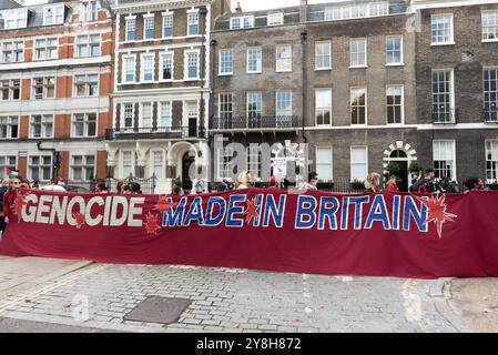 Londra, Regno Unito. 5 ottobre 2024. Un grande striscione esposto in Bedford Square dichiara "genocidio fatto in Gran Bretagna" mentre i sostenitori della Palestina si riuniscono in vista della 20a marcia nazionale per la Palestina, che ha segnato un anno da quando Israele ha lanciato la sua guerra su Gaza e la Cisgiordania occupata a seguito degli attacchi dei militanti di Hamas. Gli attivisti chiesero al Regno Unito di smettere di armare Israele, per un cessate il fuoco immediato e per la fine dell'ultima guerra israeliana contro il Libano. Crediti: Ron Fassbender/Alamy Live News Foto Stock