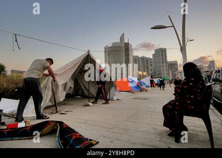 Beirut, Libano. 5 ottobre 2024. Una famiglia libanese fuggita dal sobborgo meridionale di Beirut, una roccaforte di Hezbollah filo-iraniano erige una tenda improvvisata di fronte a lussuosi edifici. Crediti: Marwan Naamani/dpa/Alamy Live News Foto Stock