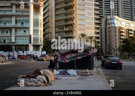 Beirut, Libano. 5 ottobre 2024. Le donne libanesi, fuggite con le loro famiglie nel sobborgo meridionale di Beirut, una roccaforte di Hezbollah filo-iraniana, si trovano vicino a una tenda improvvisata eretta di fronte a lussuosi edifici. Crediti: Marwan Naamani/dpa/Alamy Live News Foto Stock