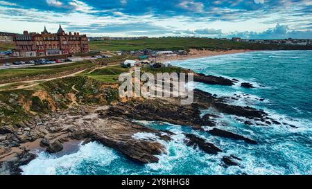 Una splendida vista costiera con scogliere rocciose e onde che si infrangono. Sullo sfondo, un edificio storico si affaccia sulla spiaggia, con spiagge sabbiose e un Foto Stock