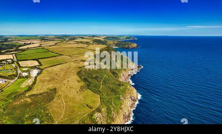 Vista aerea di una costa frastagliata con campi verdi e scogliere che si affacciano sull'oceano blu. Il paesaggio è caratterizzato da un mix di terreni agricoli e paesaggi naturali Foto Stock