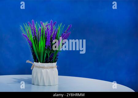 Bouquet di lavanda in vaso bianco su sfondo blu. Decorare una stanza con fiori. Deodorante per ambienti naturale Foto Stock