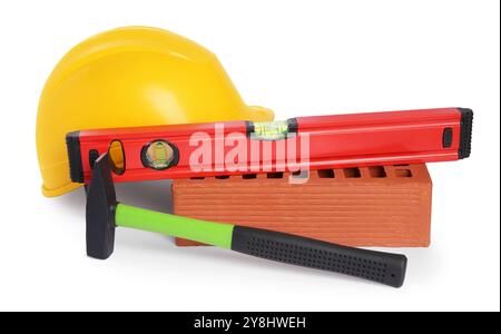 Elmetto giallo, livello edificio, martello e mattoni rossi isolati su bianco. Utensili da costruzione Foto Stock