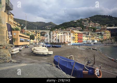 Baia con una spiaggia e barche coperte di fronte a una città iitaliana su una scogliera in una giornata nuvolosa Foto Stock