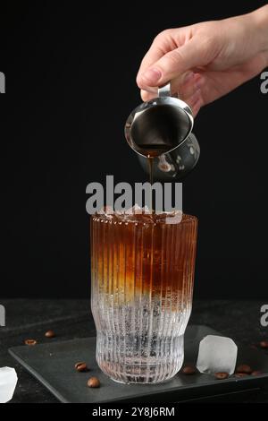 Donna che prepara rinfrescanti bevande toniche per espresso al tavolo buio, primo piano Foto Stock