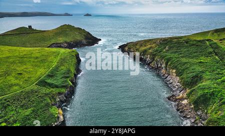 Vista aerea di un tranquillo paesaggio costiero caratterizzato da verdi colline, uno stretto corso d'acqua e l'oceano sullo sfondo. La scena cattura la bellezza di Foto Stock