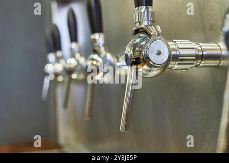 Una fila di birre d'acciaio lucide si adatta a una piccola azienda di pub Foto Stock