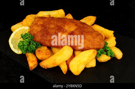 Filetto di merluzzo fritto alla birra con patatine fritte e contorno al limone Foto Stock